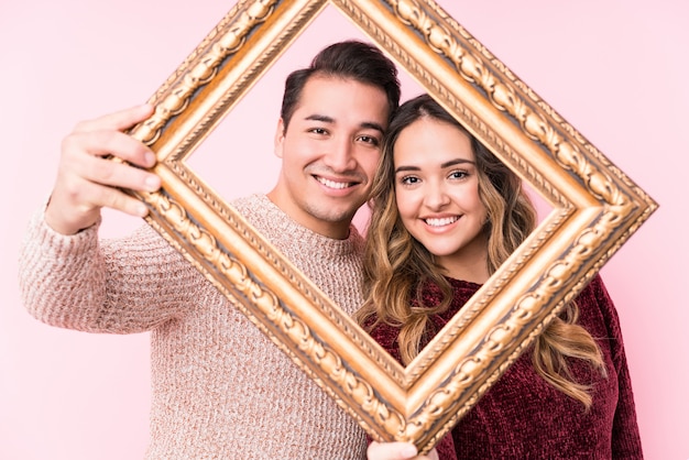 Young latin couple holding a frame