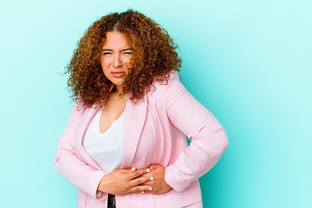 Photo young latin curvy woman isolated on blue background having a liver pain, stomach ache.