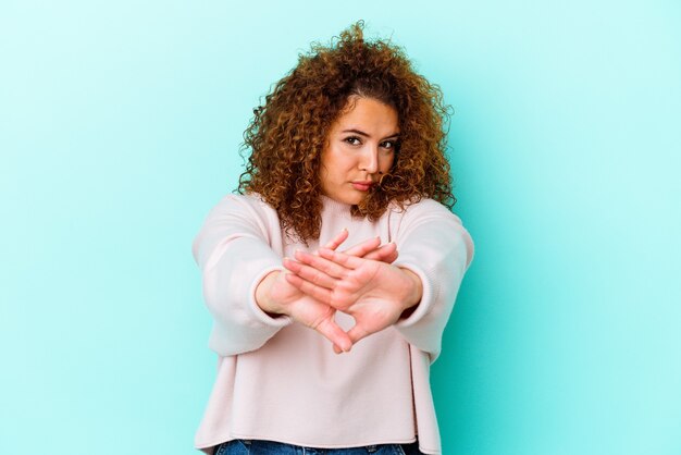 Young latin curvy woman isolated on blue wall doing a denial gesture