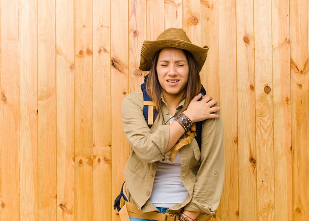 Foto giovane donna latina dell'esploratore contro il fondo di legno della parete