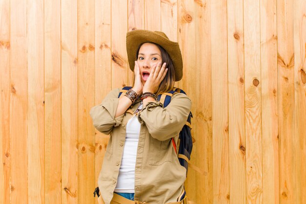 Young latin explorer woman against wooden wall background