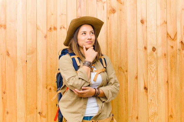 Young latin explorer woman against wooden wall background