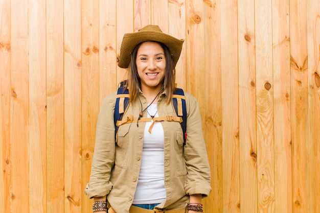 Young latin explorer woman against wooden wall background