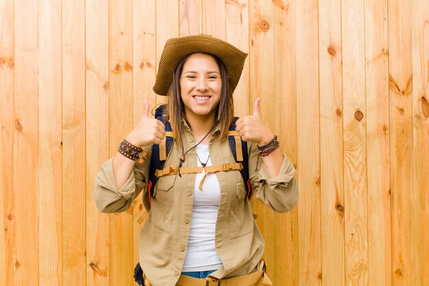 Young latin explorer woman against wooden wall background