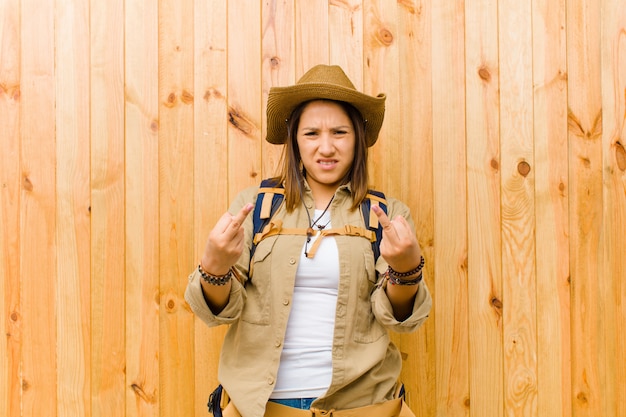 Young latin explorer woman against wooden wall background