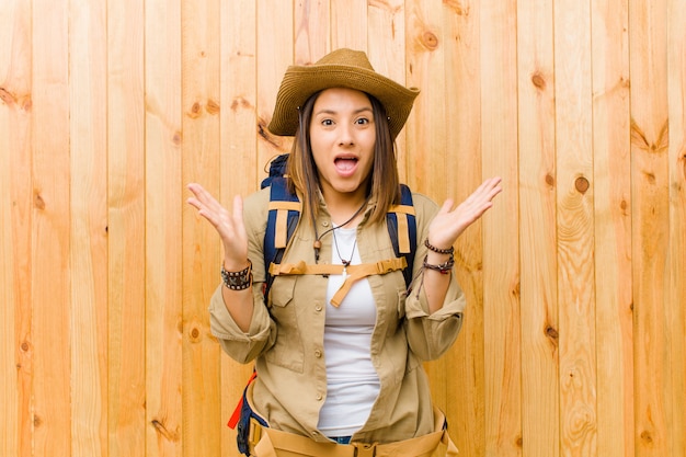 Young latin explorer woman against wooden wall wall