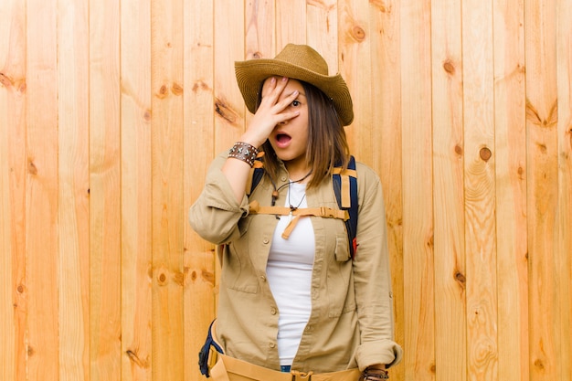 Young latin explorer woman against wooden wall wall