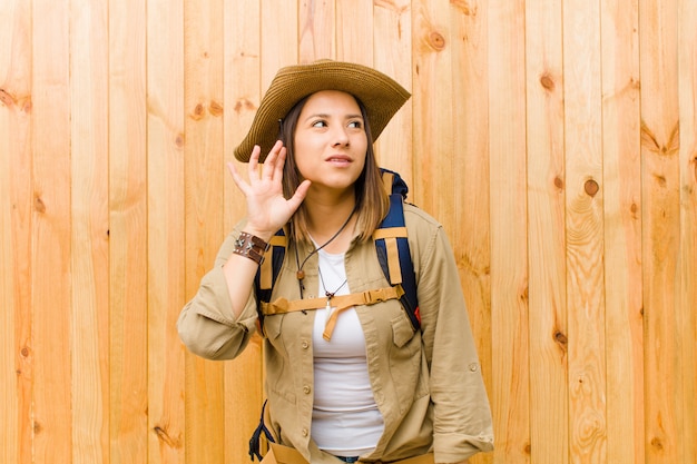 Young latin explorer woman against wooden wall