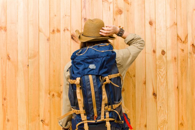 Young latin explorer woman against wooden wall