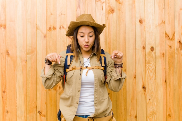 Young latin explorer woman against wooden wall