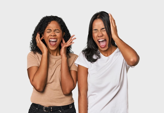 Молодые латиноамериканские друзья в студии закрывают уши руками, пытаясь не слышать слишком громкий звук.