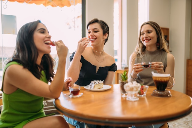 Young Latin girls sitting in cafe drinking coffee and eating cake