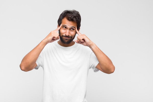 Giovane uomo latino bello che sembra perplesso e confuso, mordendosi il labbro con un gesto nervoso, non conoscendo la risposta al problema