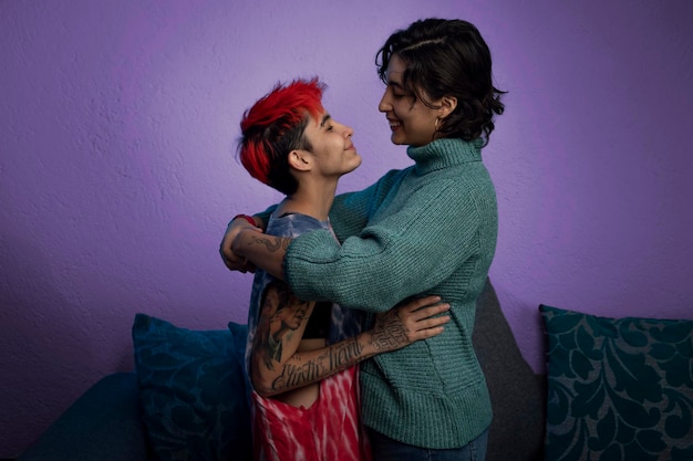 ライラックの背景でキスしようと抱き合って向かい合っている若いラテンレズビアンカップル