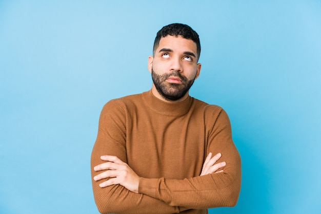 Young latin man against a blue  wall isolated tired of a repetitive task.