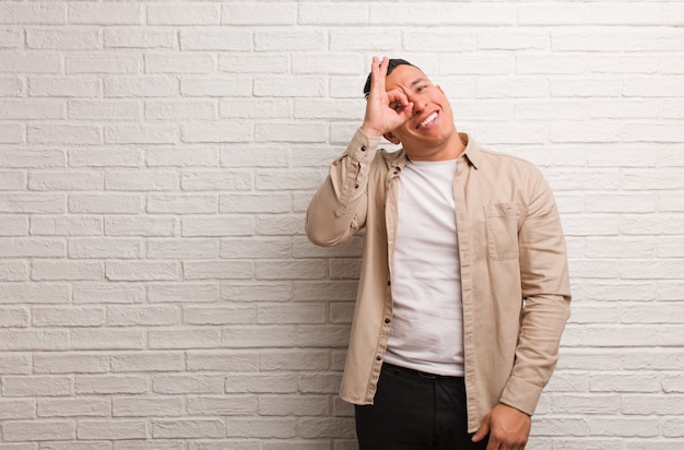 Young latin man confident doing ok gesture on eye