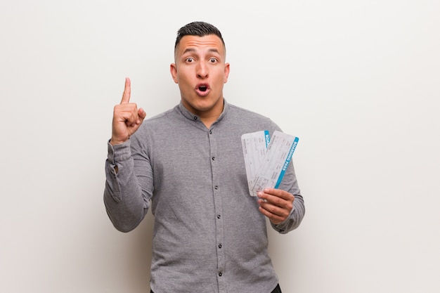 Young latin man holding an air tickets having a great idea, concept of creativity