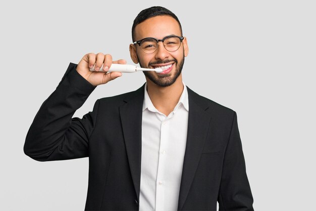 Young latin man holding an electric toothbrush isolated