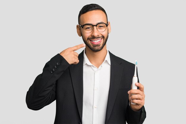 Young latin man holding an electric toothbrush isolated