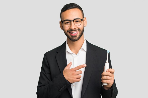 Young latin man holding an electric toothbrush isolated