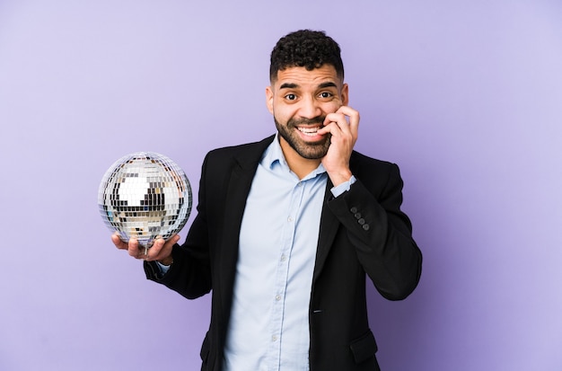 Young latin man holding a party ball isolated Young latin man holding a waffle isolated biting fingernails