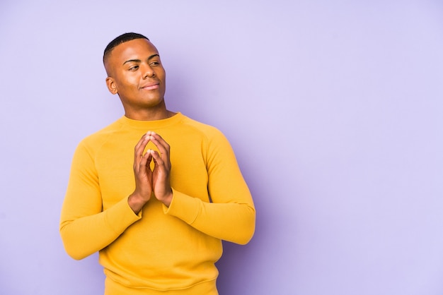 Young latin man isolated on purple making up plan in mind, setting up an idea.