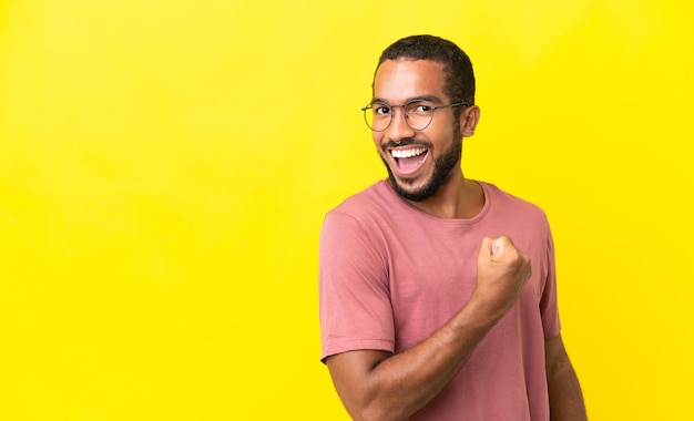 Young latin man isolated on yellow background celebrating a victory