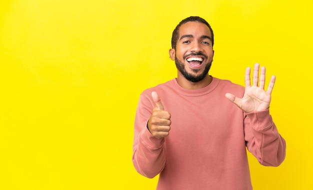 Young latin man isolated on yellow background counting six with fingers