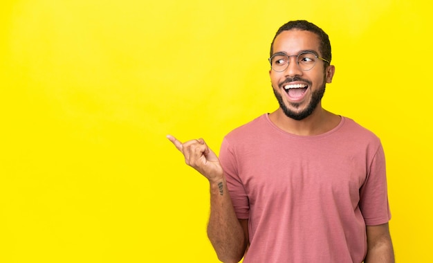 Young latin man isolated on yellow background intending to realizes the solution while lifting a finger up