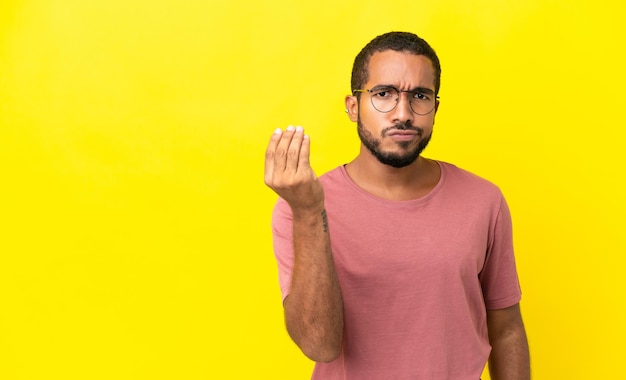 Young latin man isolated on yellow background making Italian gesture