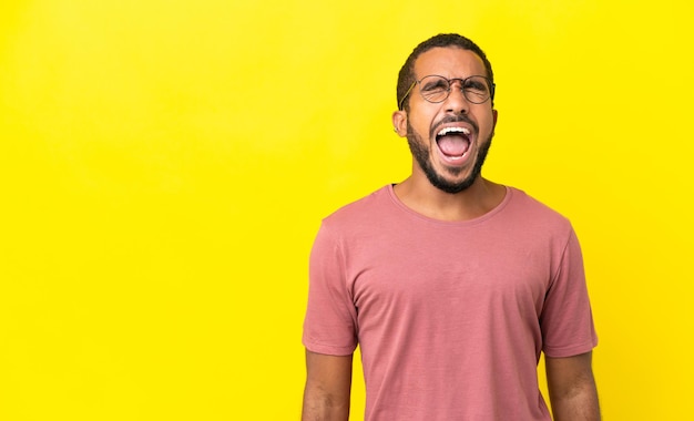 Young latin man isolated on yellow background shouting to the front with mouth wide open