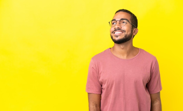 Young latin man isolated on yellow background thinking an idea while looking up