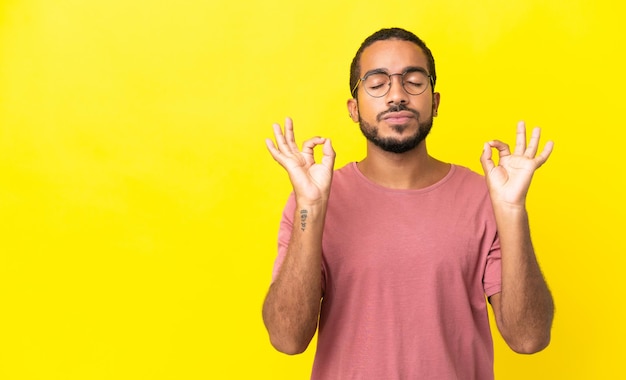 Young latin man isolated on yellow background in zen pose