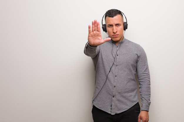 Young latin man listening to music putting hand in front