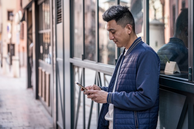 Young latin man looking at smartphone dressed casual