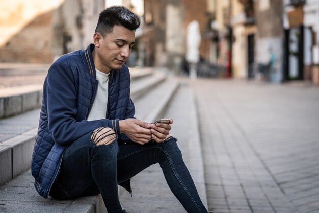 Young latin man looking at smartphone dressed casual