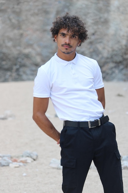 A young latin man at the sand wearing white tshirts