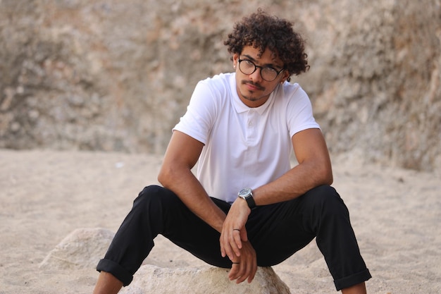 A young latin man at the sand wearing white tshirts