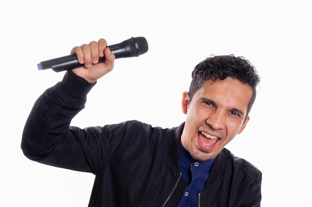 Young latin man singing and looking at the camera while holding the microphone in his hand