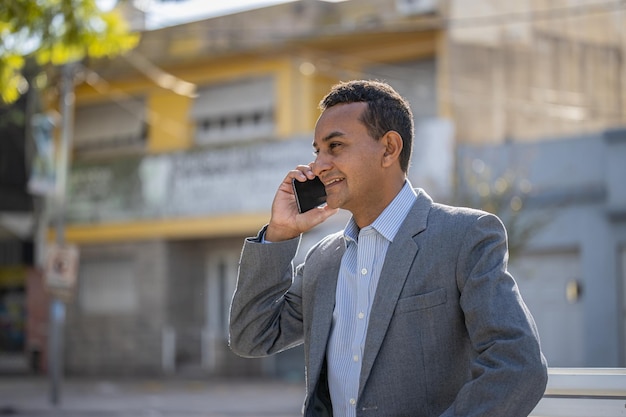 Young latin man sitting on a square bench talking on mobile phone with copy space