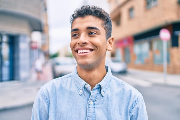 Foto giovane uomo latino che sorride felice camminando in città