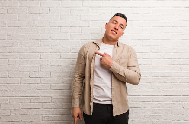 Young latin man smiling and pointing to the side