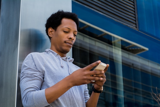 Young latin man typing on his phone.