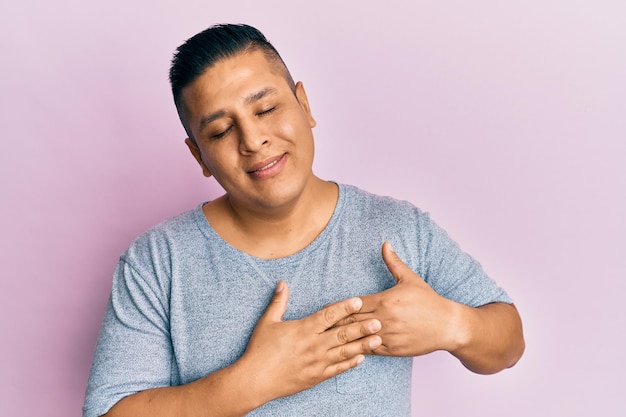 Young latin man wearing casual clothes smiling with hands on chest eyes closed with grateful gesture on face health concept