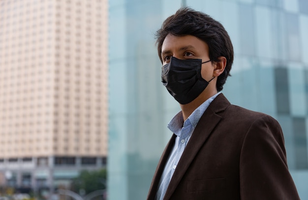 코로나 바이러스 전염병 기간 동안 보호 이유로 얼굴 마스크를 쓰고 젊은 라틴 남자
