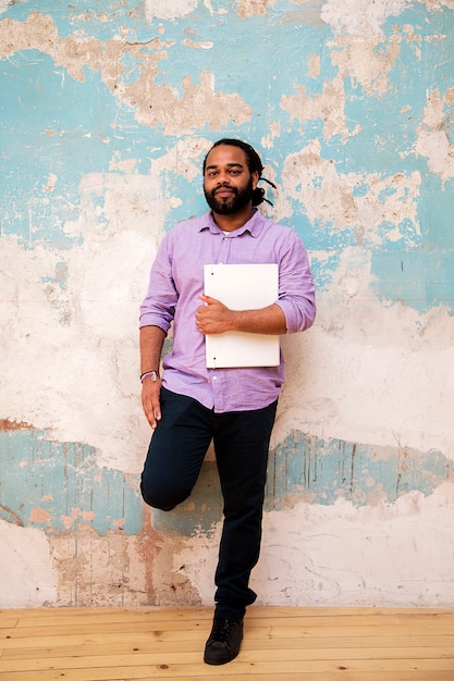 Young latin man with file by the wall