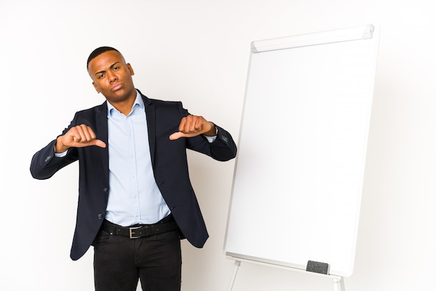 Young latin man with a white board on a white wall feels proud and self confident, example to follow.