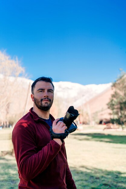 Young latin photographer holding a photo camera outdoors portrait