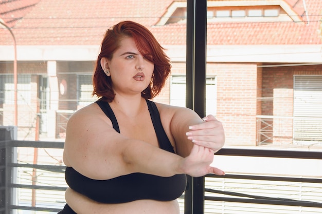 Young latin plus size woman in black sportswear training stretching arms and hands