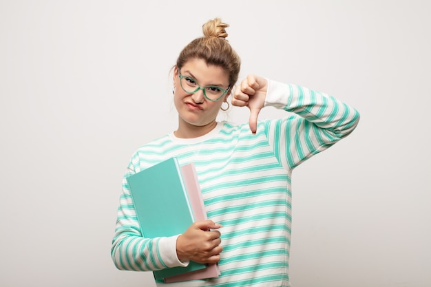 Young latin pretty woman  against flat wall with books. student concept